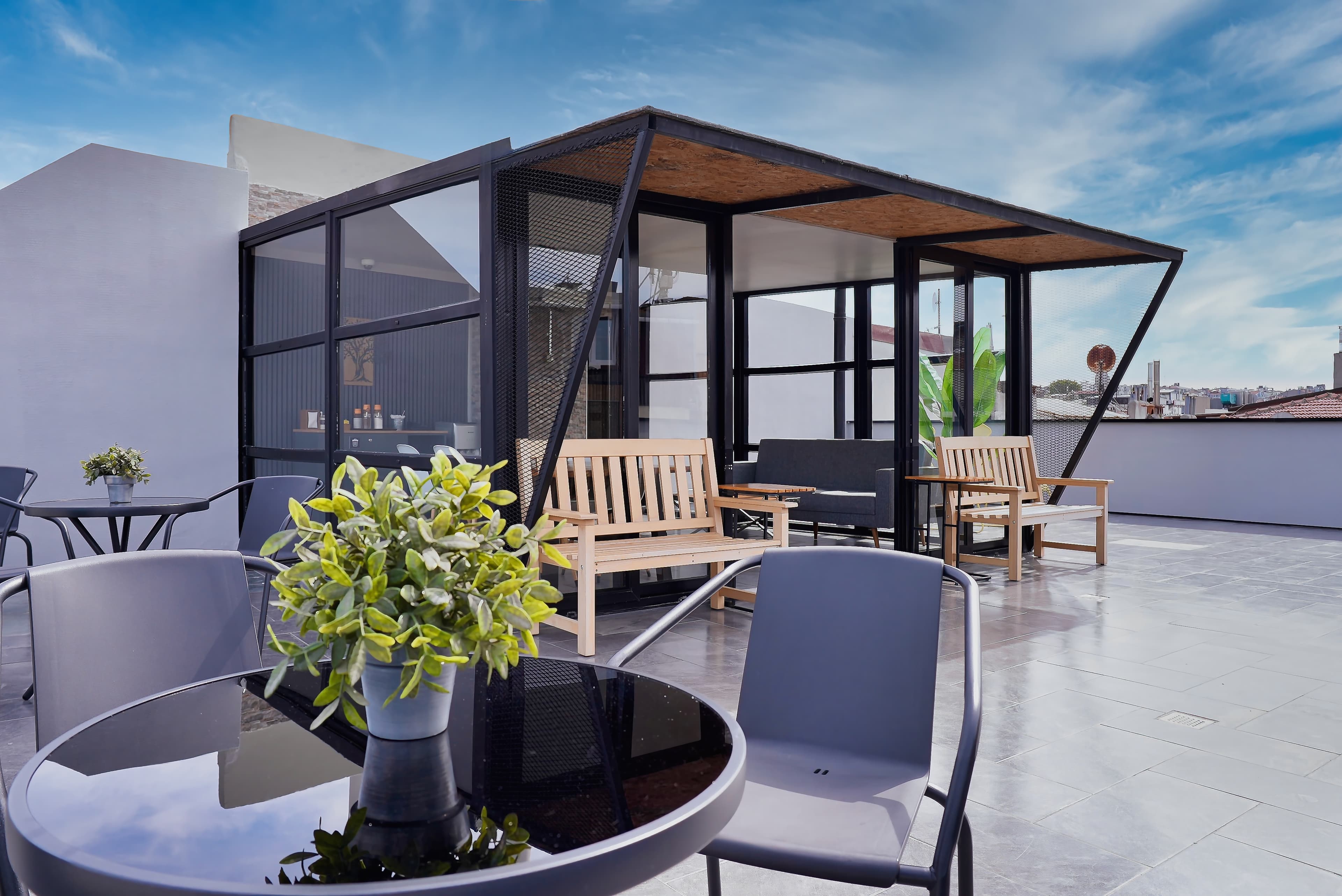 Open rooftop deck with bistro tables beside the glass sunroom