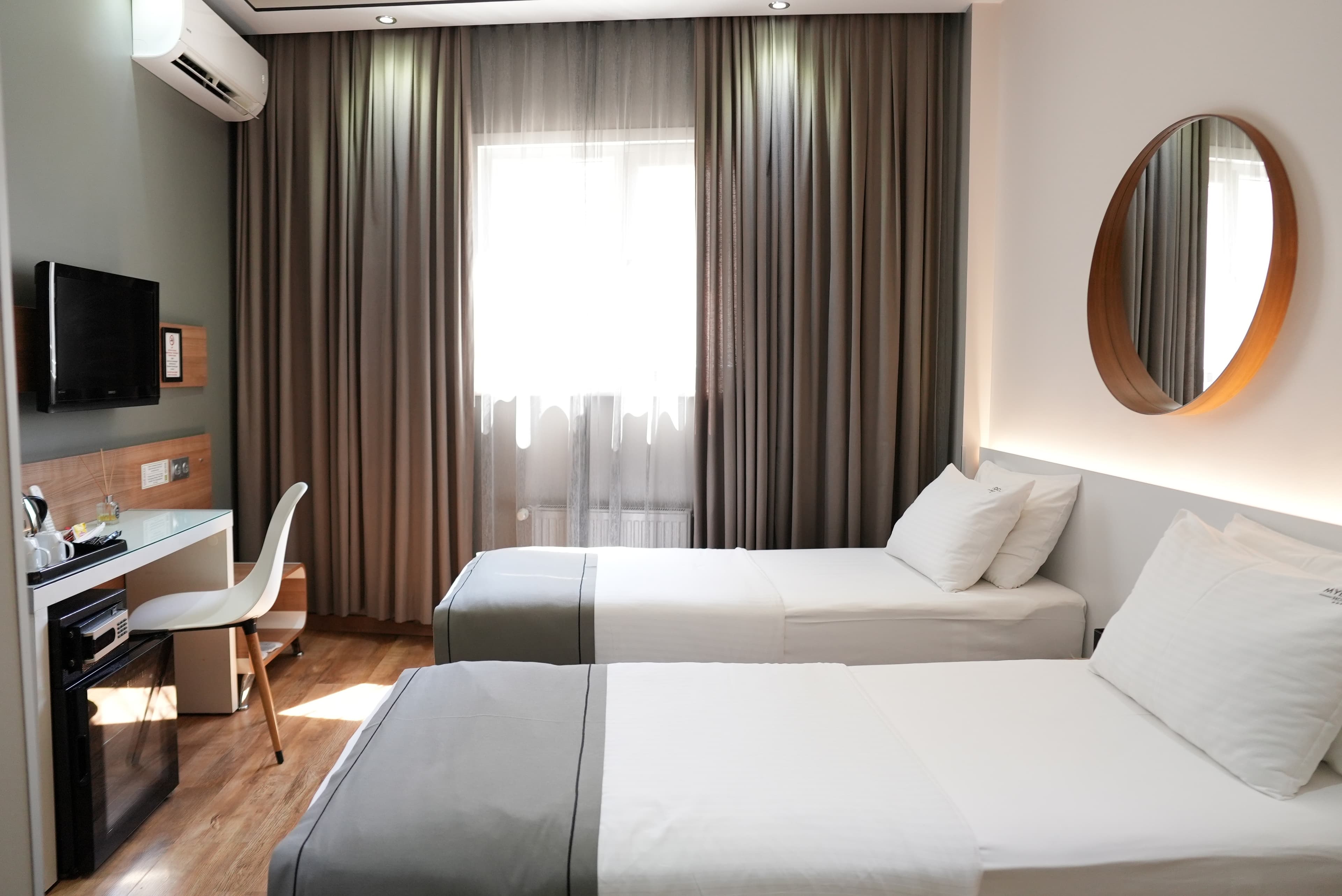 Standard twin: the room from the corner, with wall-mounted TV, desk and minibar